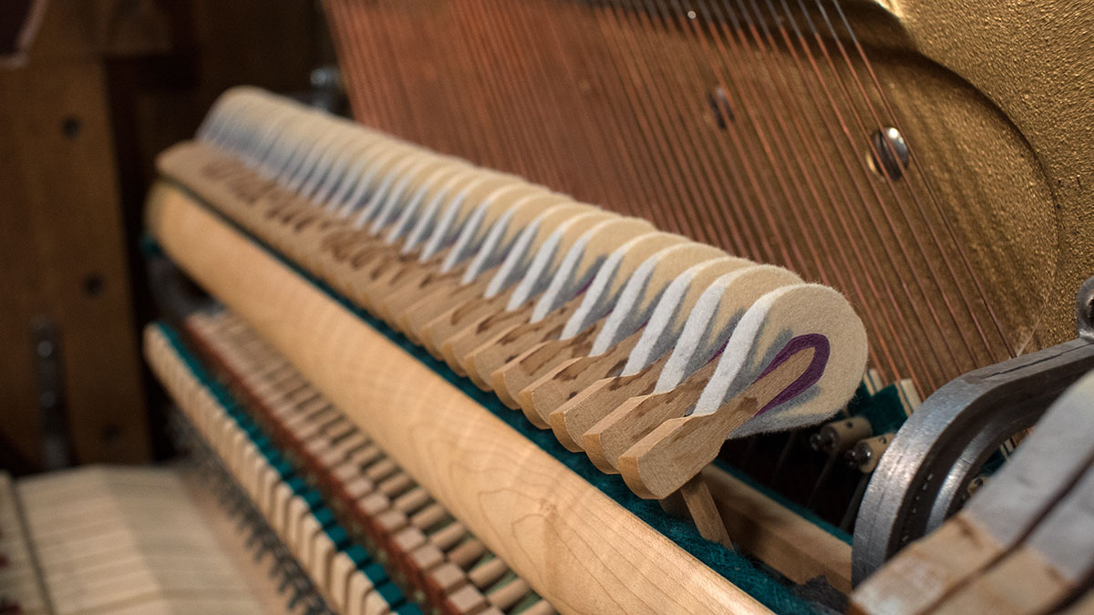 Technician voicing a piano hammer with a needle tool
